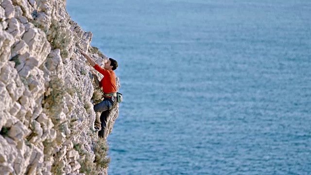 在阳光下，男人在悬崖峭壁上攀岩视频下载