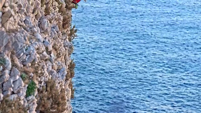在夕阳下，女人爬上悬崖峭壁视频素材