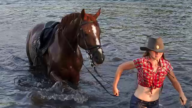 女孩穿着衣服和她的马从湖里出来视频素材
