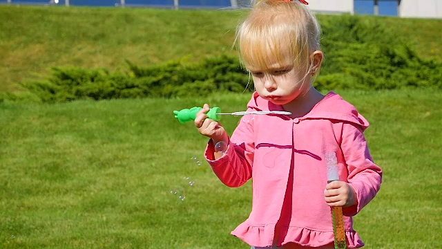 慢镜头:3岁的小女孩在公园里吹肥皂泡。视频下载
