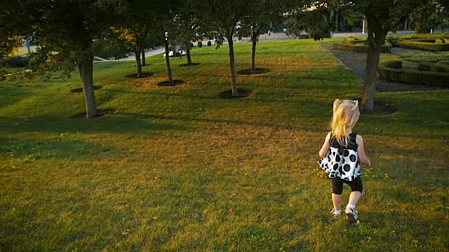 慢镜头:小女孩在夏季公园的绿草地上奔跑了三年。视频下载