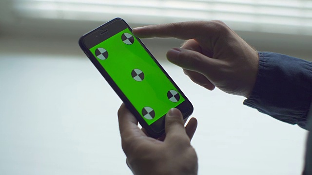 男人持有智能手机触摸屏与绿色屏幕色度键自定义内容视频素材