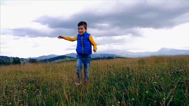 有趣的小男孩在山中散步时跳跃视频素材