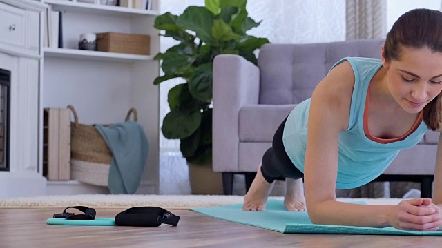 年轻的西班牙女子在家里锻炼时保持平板支撑的姿势视频下载