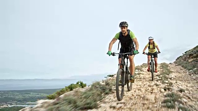 一对夫妇在一条岩石路上骑着自行车下山视频下载