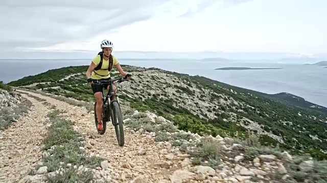 女山地自行车骑在一个山脊上的岩石道路俯瞰大海视频素材