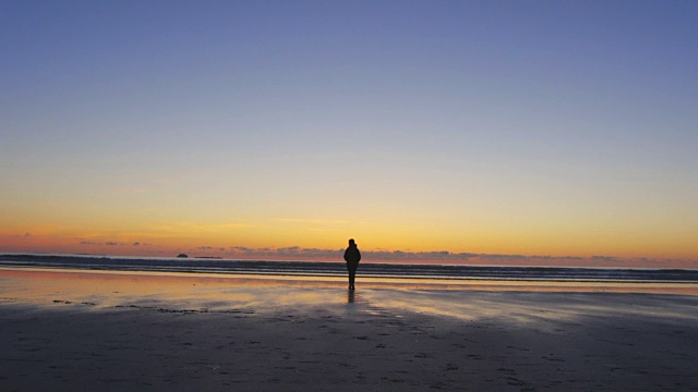 日落时分，在海滩上散步的剪影女人视频素材