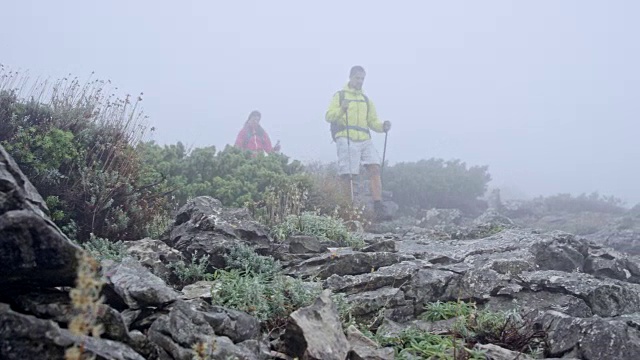 男人和女人沿着一条砾石小道走下迷雾弥漫的山视频素材