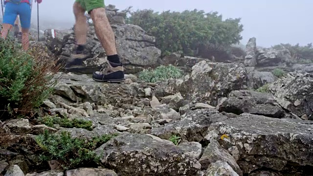 两对夫妇在一条多岩石的小道上走在雾蒙蒙的山上视频素材