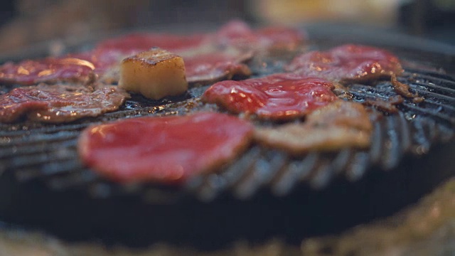 烹饪烧烤，在炉子上的木炭上烤。关闭牛肉烤在日本餐厅。用于烧烤或日式食物的生牛肉片视频素材