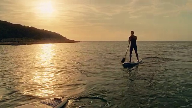 日落时分，一对夫妇在他们的sup上划桨视频下载
