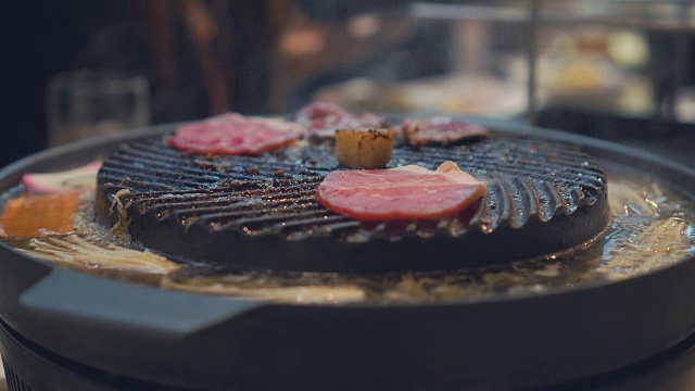 烹饪烧烤，在炉子上的木炭上烤。关闭牛肉烤在日本餐厅。用于烧烤或日式食物的生牛肉片视频素材