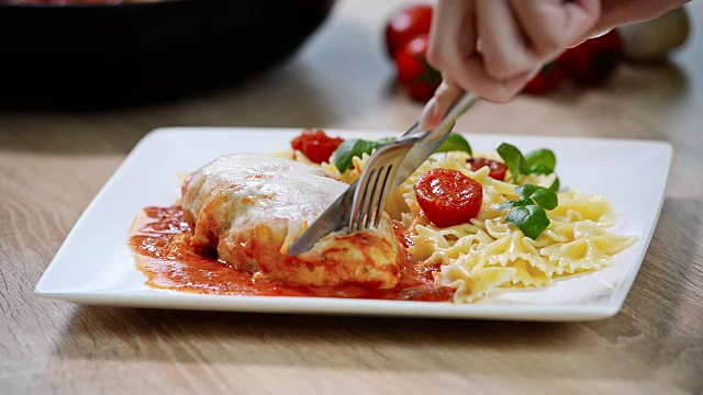 意大利食物:鸡肉配西红柿和意大利面特写。女孩吃视频下载