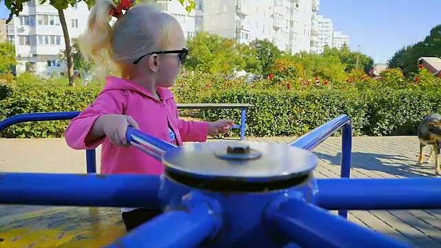 慢镜头:快乐的女孩戴着太阳镜在城市公园里荡秋千。视频素材