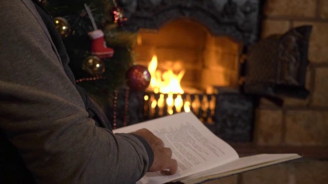 圣诞夜，老人在壁炉和圣诞树旁看书视频素材