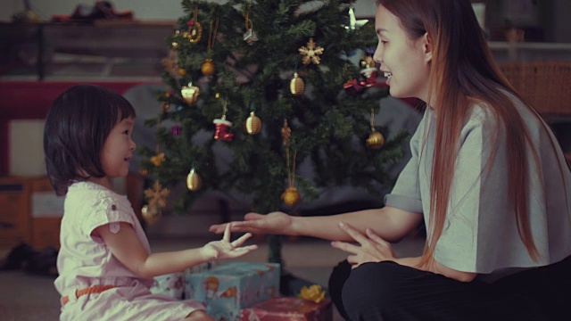 年轻的母亲和女婴用装饰品装饰圣诞树视频素材