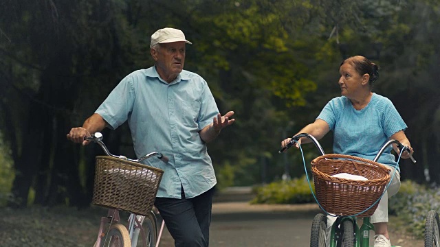 两个骑着自行车的老人在公园里聊天视频素材