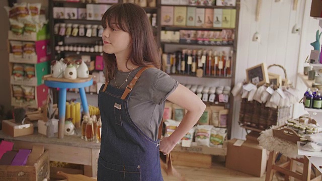 女熟食店老板系围裙和站在商店双臂交叉视频素材