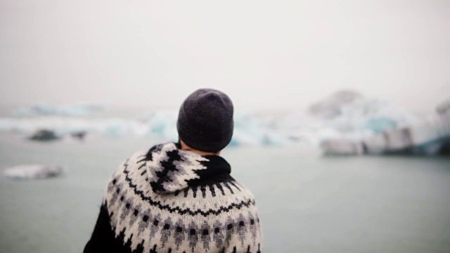 年轻的胡子男子站在Jokulsalon冰礁湖，看着冰川，冰岛北部的自然视频素材