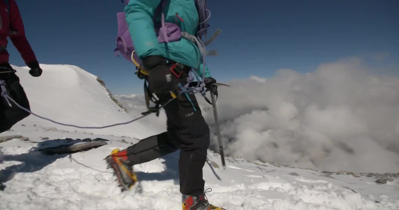 在慢镜头中，两个女人用冰镐和冰爪爬山。视频购买