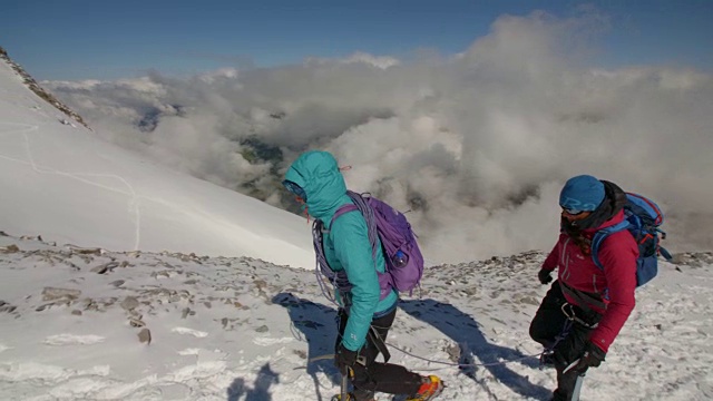 两名女登山家在云上微笑着攀登冰川。视频素材