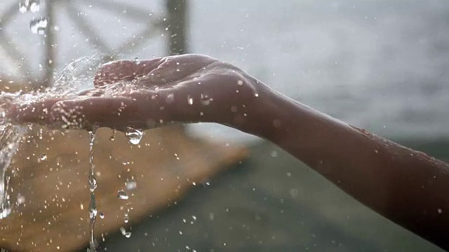 清澈的水流入一个女人的手中。缓慢的运动。视频素材