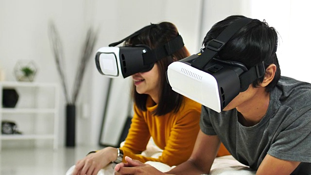 年轻的亚洲夫妇使用虚拟现实眼镜玩视频下载