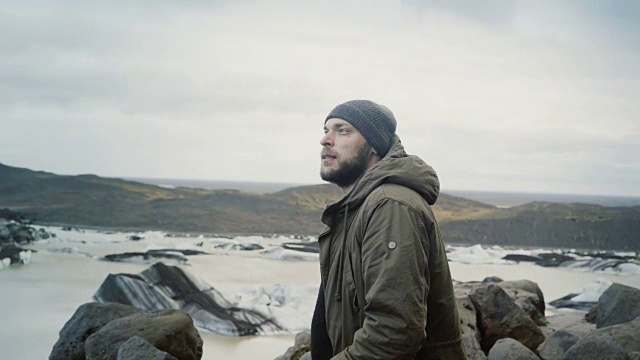 一个年轻的旅行者站在山顶上，在冰岛的Vatnajokull冰泻湖上观看冰川视频素材