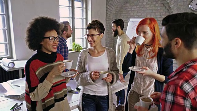 一群有创意的商务人士在休闲的办公室喝咖啡和交流。视频素材