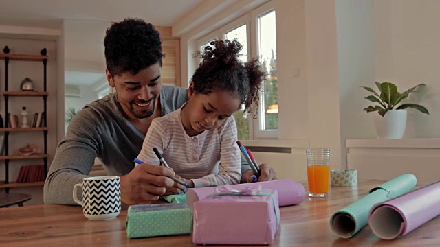 快乐的非裔美国父亲和女儿在家里装饰礼盒。视频素材