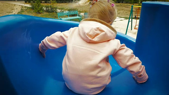 慢镜头:三岁小女孩从滑梯上下来。视频下载