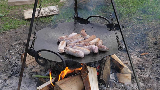 美味多汁的香肠在火上煎锅，烧烤视频下载