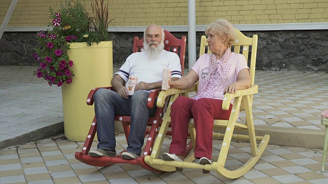 老人和老太太坐在摇椅上休息，吃着爆米花视频下载
