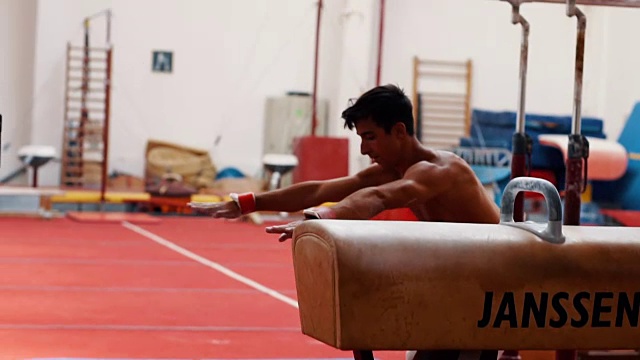 年轻的体操运动员在鞍马上表演双腿旋转视频下载