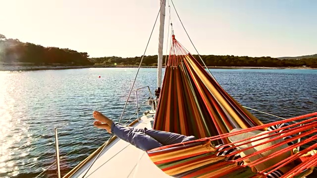 SLO MO女人在一艘帆船的吊床上放松视频素材