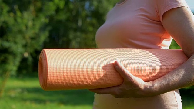 近距离的一个运动垫子在一个年老的运动妇女的手中视频素材