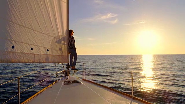 日落时分，站在帆船船头的女人视频素材