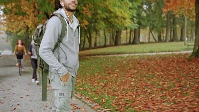 多民族的年轻人听音乐，而骑他的长板在一个公园视频素材