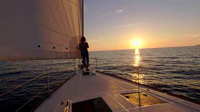 日落时分，一个女人走在帆船上视频素材