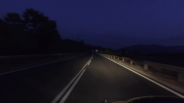 在漆黑的夜晚开着前灯行驶在乡村道路上视频素材