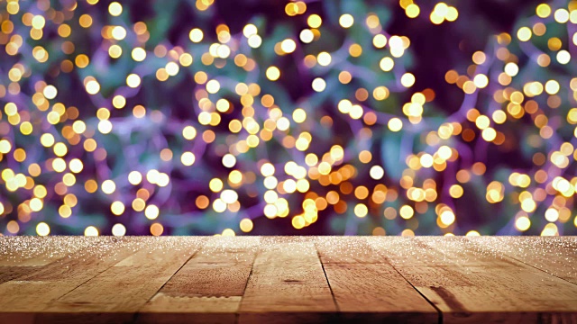 木质桌面与闪烁的装饰灯bokeh在圣诞树在晚上的背景视频下载