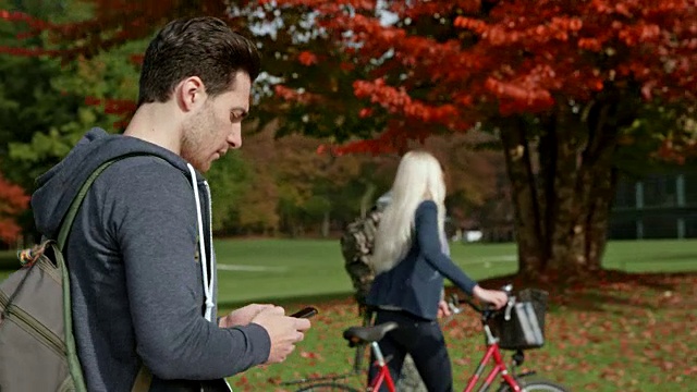 TS白人男学生在公园散步时滚动手机视频素材