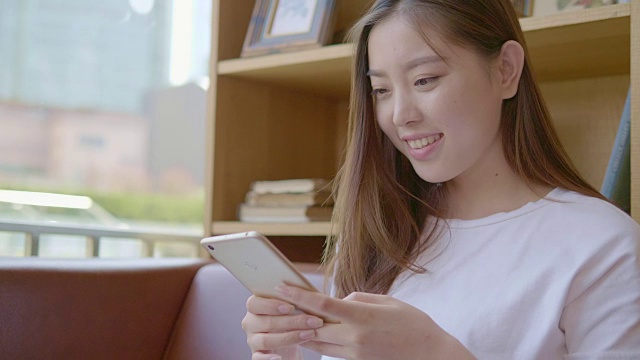 年轻女子在咖啡馆用智能手机视频下载