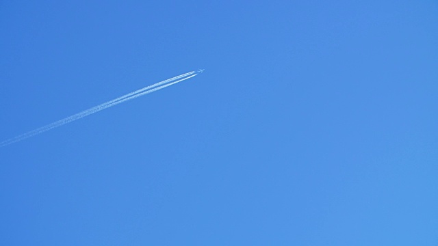 一架喷气式客机在高空飞行，在清澈的蓝天上留下了尾迹。视频素材