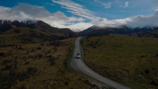 鸟瞰图SUV驾驶在沙漠向雪山山峰在新西兰视频素材