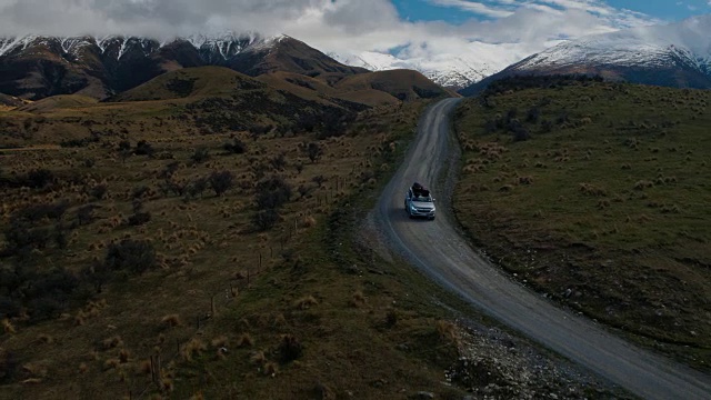 鸟瞰图SUV驾驶在沙漠向雪山山峰在新西兰视频素材