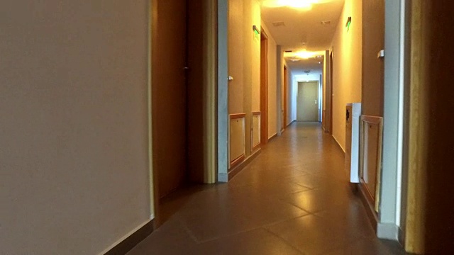 在有许多门的酒店走廊里散步。到达公寓门口，4k稳定器视频素材