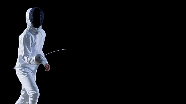 装备齐全的熟练击剑运动员训练用花剑。他练习攻击，防御，跳跃，刺和弓步。拍摄孤立的黑色背景。视频素材