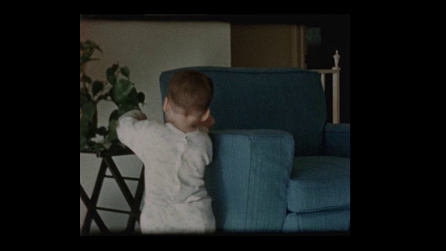 1960年，可爱的蹒跚学步的小男孩在客厅里走来走去视频素材