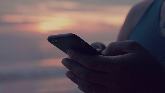 日落时分，一名男子在海上用智能手机打字视频素材